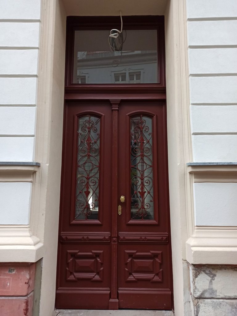Odnowione bordowe drzwi wejściowe z przeszkleniami