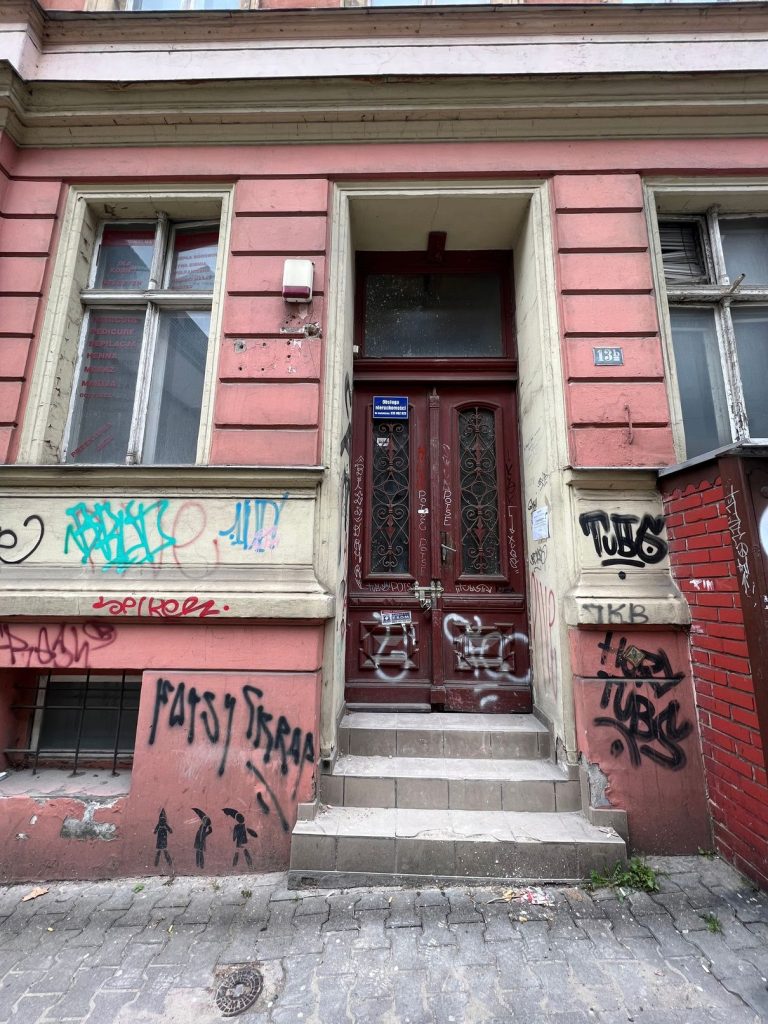 Wejście do kamienicy przed remontem – graffiti na elewacji